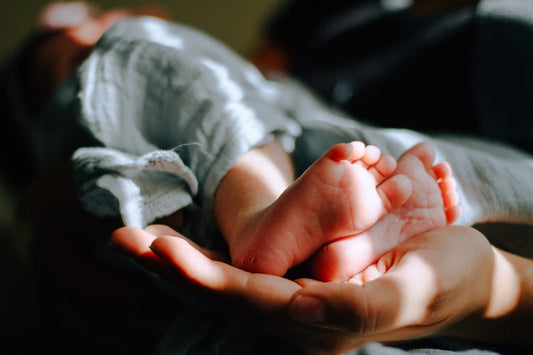 Parent holding newborn baby feet